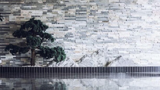 A pool with a tiled edge and a wall with a stone mosaic pattern. - Xinfanghua Hotel (Hejian Xinyulou Branch) (Hejian)