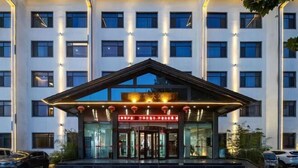 A modern hotel entrance with a glass facade, a central entrance with a red sign, and a staircase leading up to the doors. - Xinfanghua Hotel (Hejian Xinyulou Branch) (Hejian)