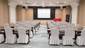 A conference room with rows of tables and chairs, a projector screen, and a red podium. - Xinfanghua Hotel (Hejian Xinyulou Branch) (Hejian)