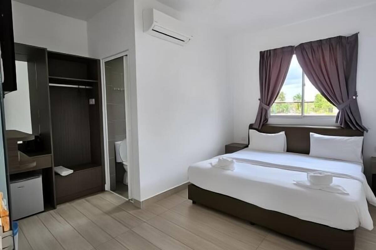 A hotel room with a bed, a wardrobe, and an air conditioning unit.