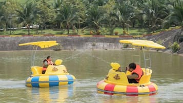 Two yellow watercraft with passengers, surrounded by water and palm trees.