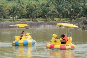 Two yellow watercraft with passengers, surrounded by water and palm trees.