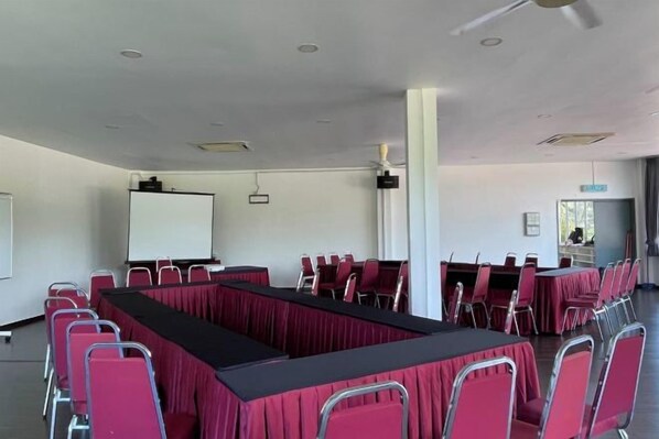 A conference room with a long table, chairs, a whiteboard, and a projector screen.