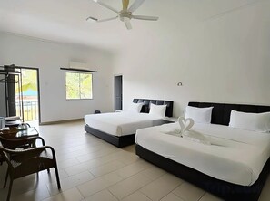 A hotel room with two beds, a ceiling fan, a window with a view, and a table with chairs.