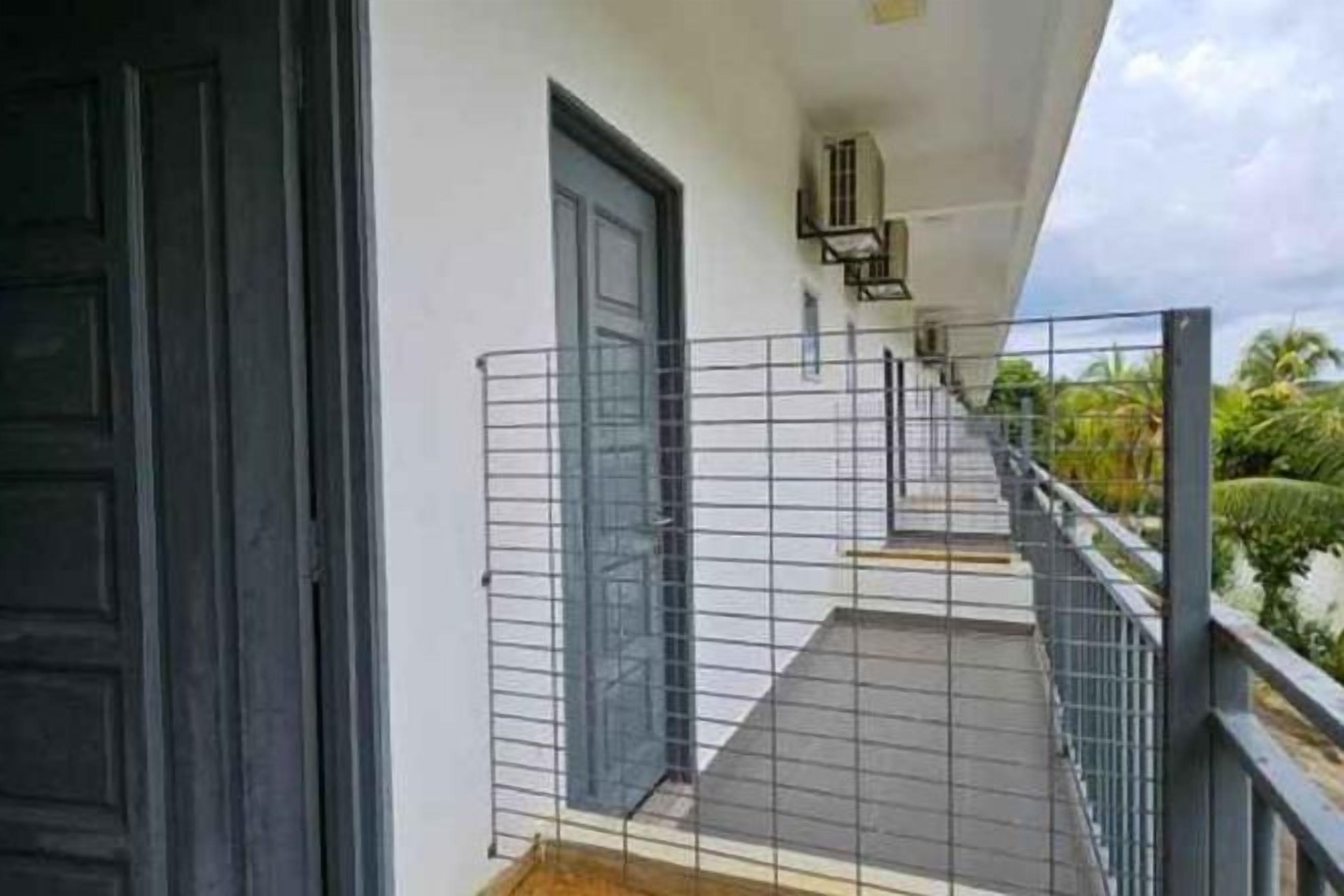 A balcony with a metal railing, a door, and a staircase leading to an upper level.