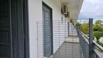 A balcony with a metal railing, a door, and a staircase leading to an upper level.
