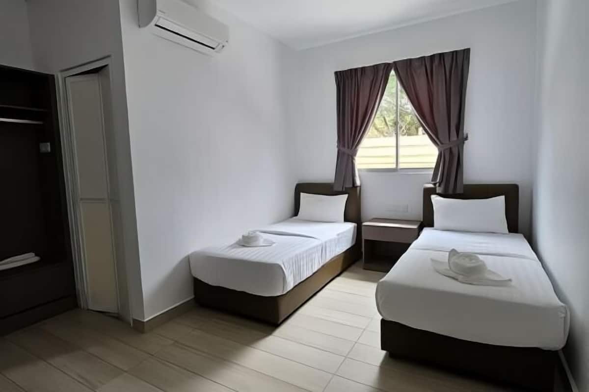 A hotel room with two beds, a wardrobe, an air conditioning unit, and a window with curtains.