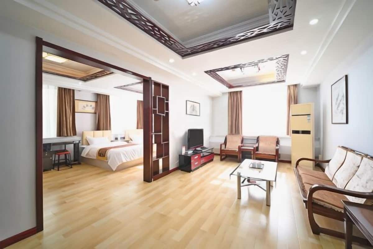 A hotel room with a bed, a desk, a sofa, a TV, and a coffee table.
