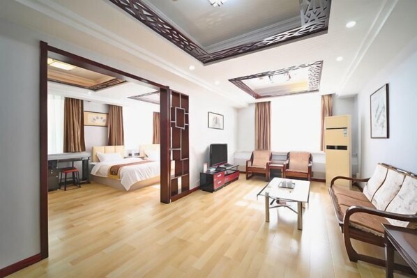 Ein Hotelzimmer mit Bett, Schreibtisch, Sofa, Fernseher und Couchtisch.