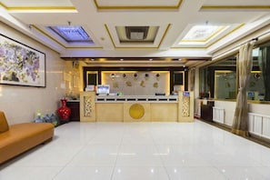 Zona de recepción de un hotel con mostrador, un sofá y un ventanal grande.