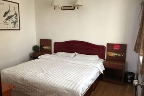 A hotel room with a bed, bedside tables, a nightstand, a wall-mounted lamp, and a framed picture. - Jingxuanlou Hotel（near the great wall） (Qinhuangdao)