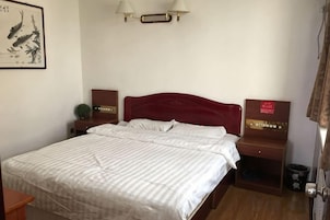Habitación de hotel con una cama, mesitas de noche, lámpara de pared y un cuadro enmarcado.