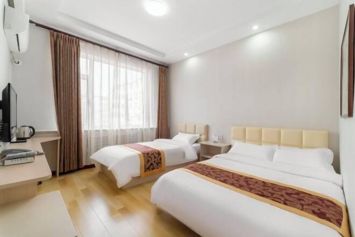 A hotel room with two beds, a desk with a coffee maker, and a TV.
