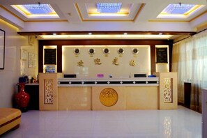 A reception area with a counter, decorative wall, and a large vase. - Jingxuanlou Hotel(near the great wall) (Qinhuangdao)