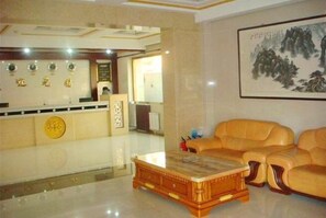 A lobby with a reception desk, a sofa, and a coffee table. - Jingxuanlou Hotel(near the great wall) (Qinhuangdao)