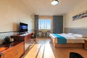 A hotel room with a bed, a desk with a computer, a chair, a small table, and a window with curtains. - Mijia Shenke Business Hotel (Wuhuwan Yuqu Branch) (Wuhu)