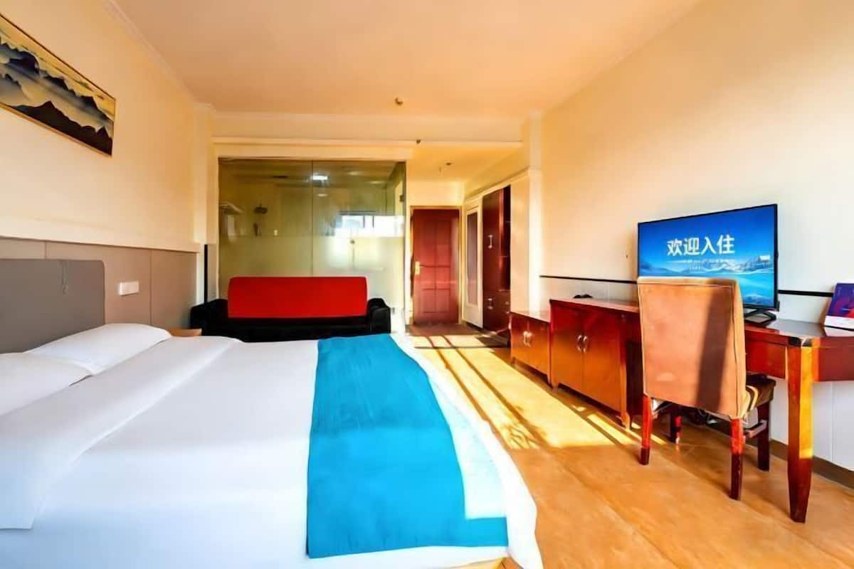 Ein Hotelzimmer mit Bett, Schreibtisch, Stuhl und Fernseher.