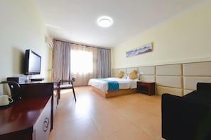 A hotel room with a bed, a desk with a computer, a chair, and a TV.
