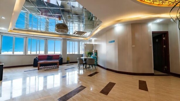 Een ruime lobby met een hoge plafond, grote ramen, een zithoek en een receptiebalie.