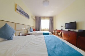 A hotel room with two beds, a television, a desk, and a chair.