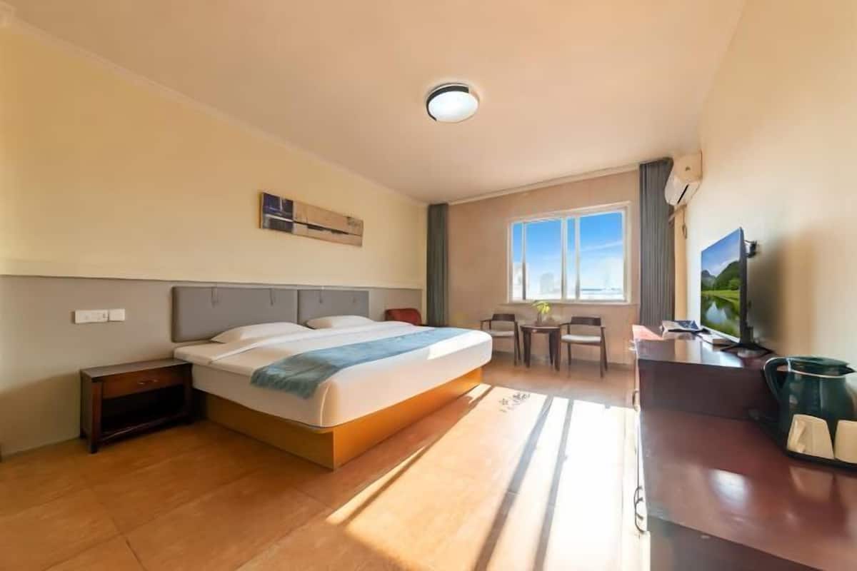 Ein Hotelzimmer mit Bett, Nachttisch, Schreibtisch, Stuhl und Fernseher.