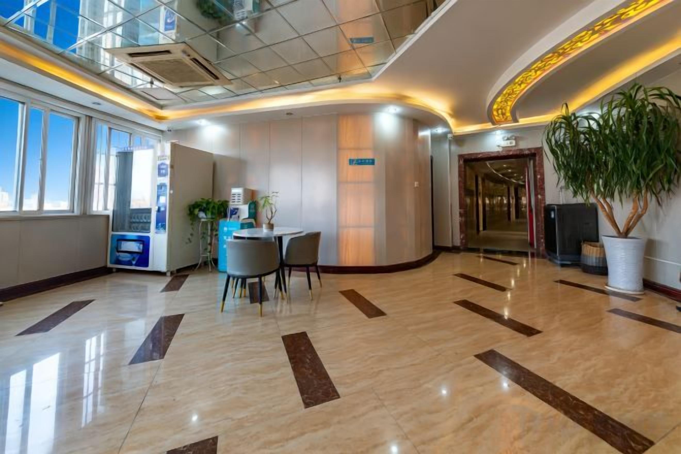 Rebuda d'hotel amb taulell de recepció, zona de seients i una planta gran en test.