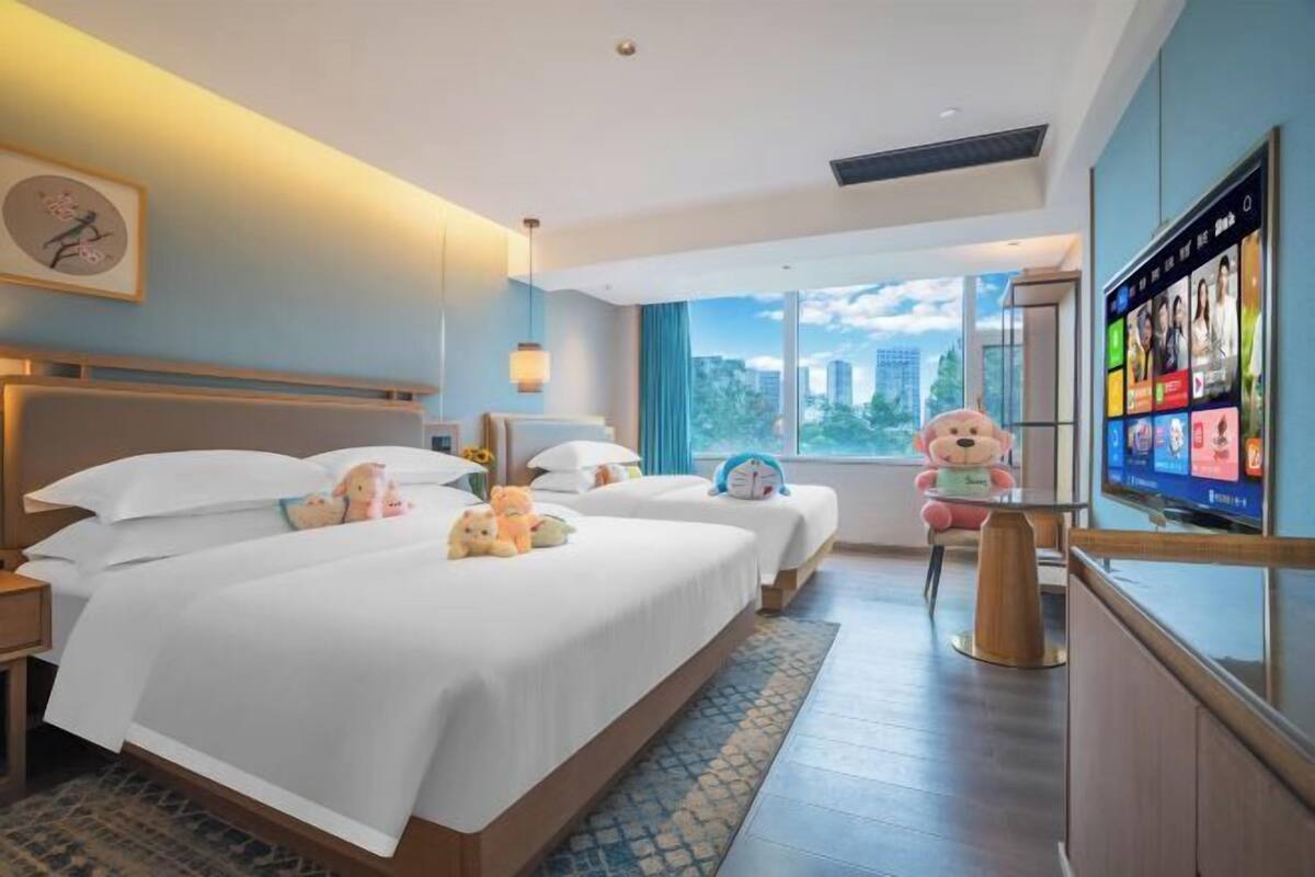 Ein Hotelzimmer mit einem großen Bett, einem Fernseher und Blick auf die Stadt.