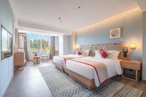 Habitación de hotel moderna con una cama grande, mesitas de noche, un escritorio y vistas al exterior.