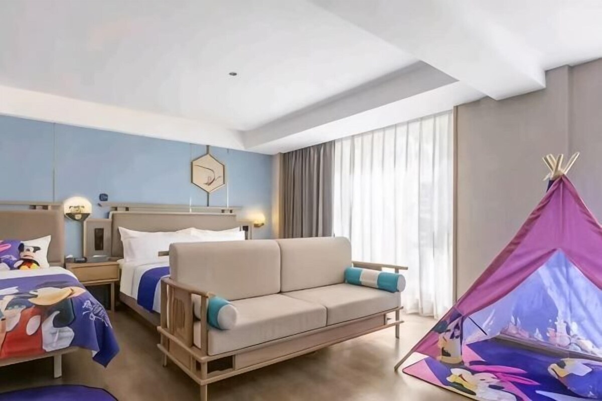Une chambre d’hôtel avec un canapé, un lit, une table de chevet, une lampe, une fenêtre avec des rideaux et une structure ressemblant à une tente.