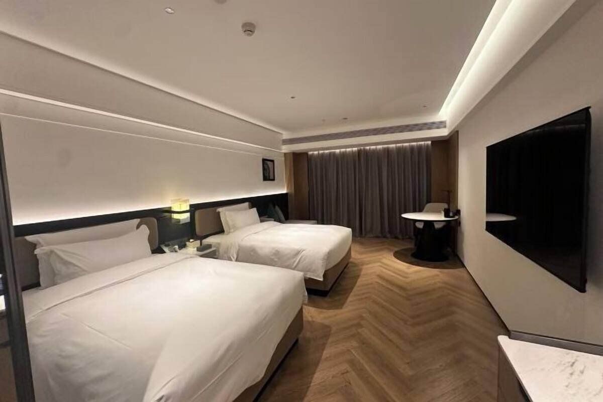 Ein Hotelzimmer mit zwei Betten, einem Fernseher, einem Schreibtisch und einem Stuhl.