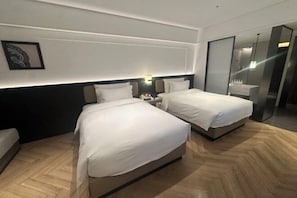 A hotel room with two beds, a nightstand, a wall-mounted lamp, and a modern bathroom with a glass shower. - Kunming Guandu Muyunpan Garden Resort Hotel (Hai Le World Shijicheng Changhong West Road Branch) (Kunming)