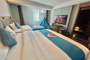 Ein Hotelzimmer mit zwei Betten, einem Fernseher, einem Schreibtisch und einem Fenster mit Vorhängen.