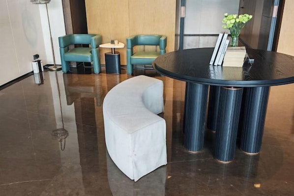 A lobby with a round table, two teal chairs, a white sofa, and a small side table. - Kunming Guandu Muyunpan Garden Resort Hotel (Hai Le World Shijicheng Changhong West Road Branch) (Kunming)