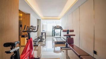 A hotel gym with exercise equipment, a treadmill, and a bench.