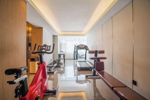 Une salle de sport d’hôtel équipée de matériel d’exercice, d’un tapis de course et d’un banc.