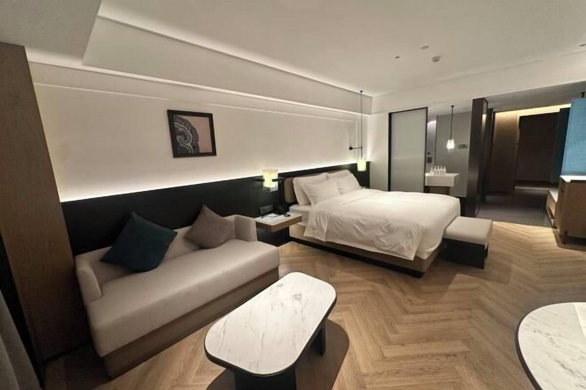 Ein modernes Hotelzimmer mit Bett, Sofa, Couchtisch und Schreibtisch.