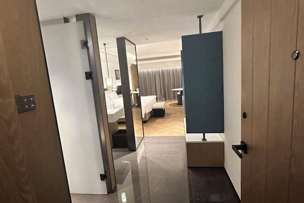 Un couloir d’hôtel avec un lit, un bureau et un miroir.