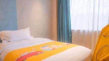 A hotel room with a bed, a window with curtains, and a yellow blanket.