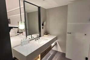Une salle de bain moderne avec un grand miroir, deux lavabos et un espace douche.