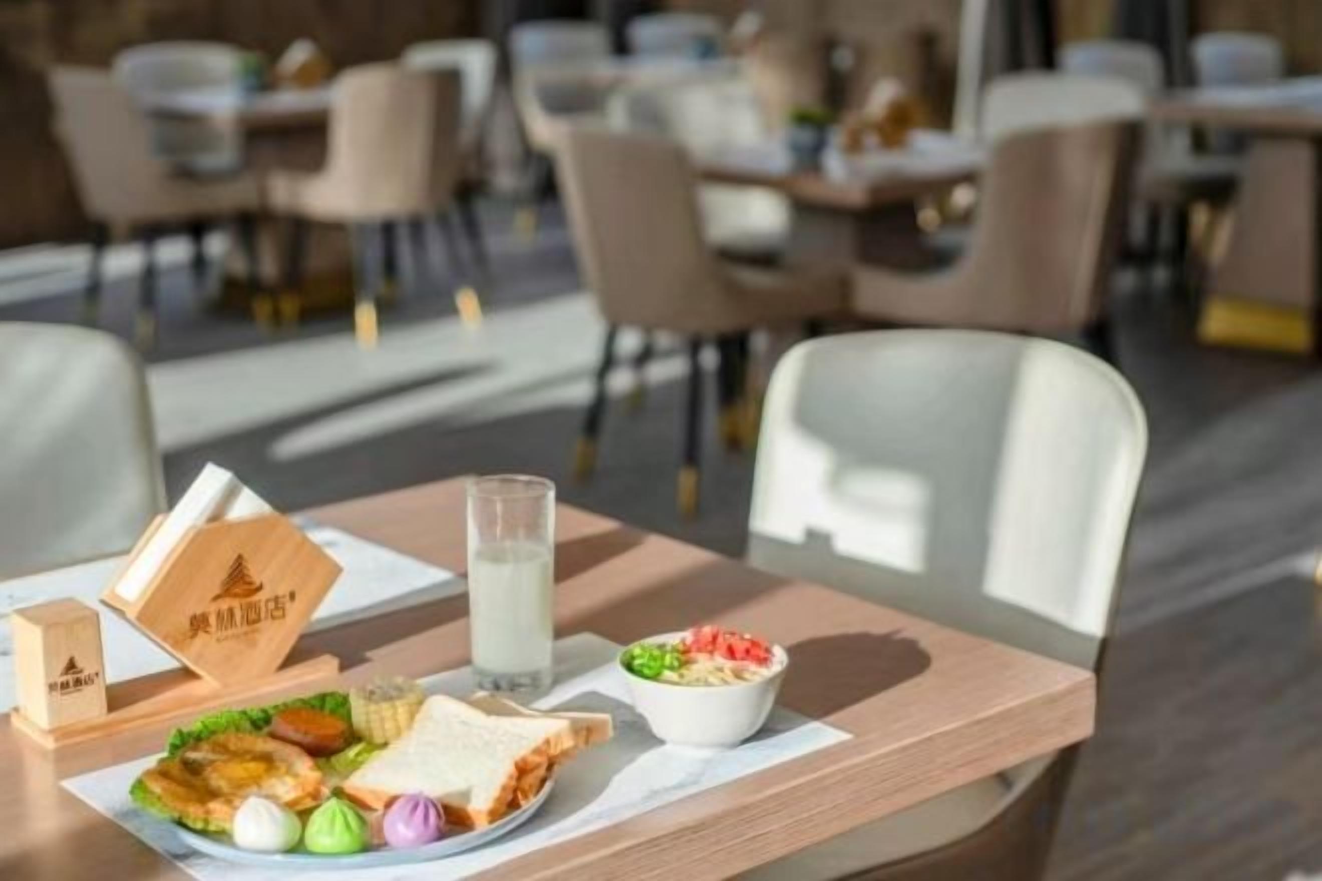 A dining table with a meal, a glass of milk, and a bowl of salad in a restaurant setting.