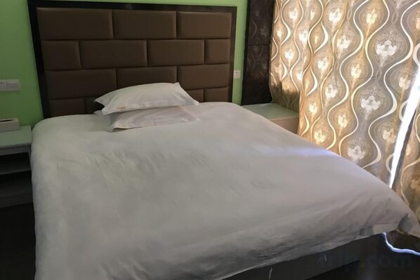 A bed with a headboard, pillows, and a blanket. - Ai Jiu Hotel (Shanghai)