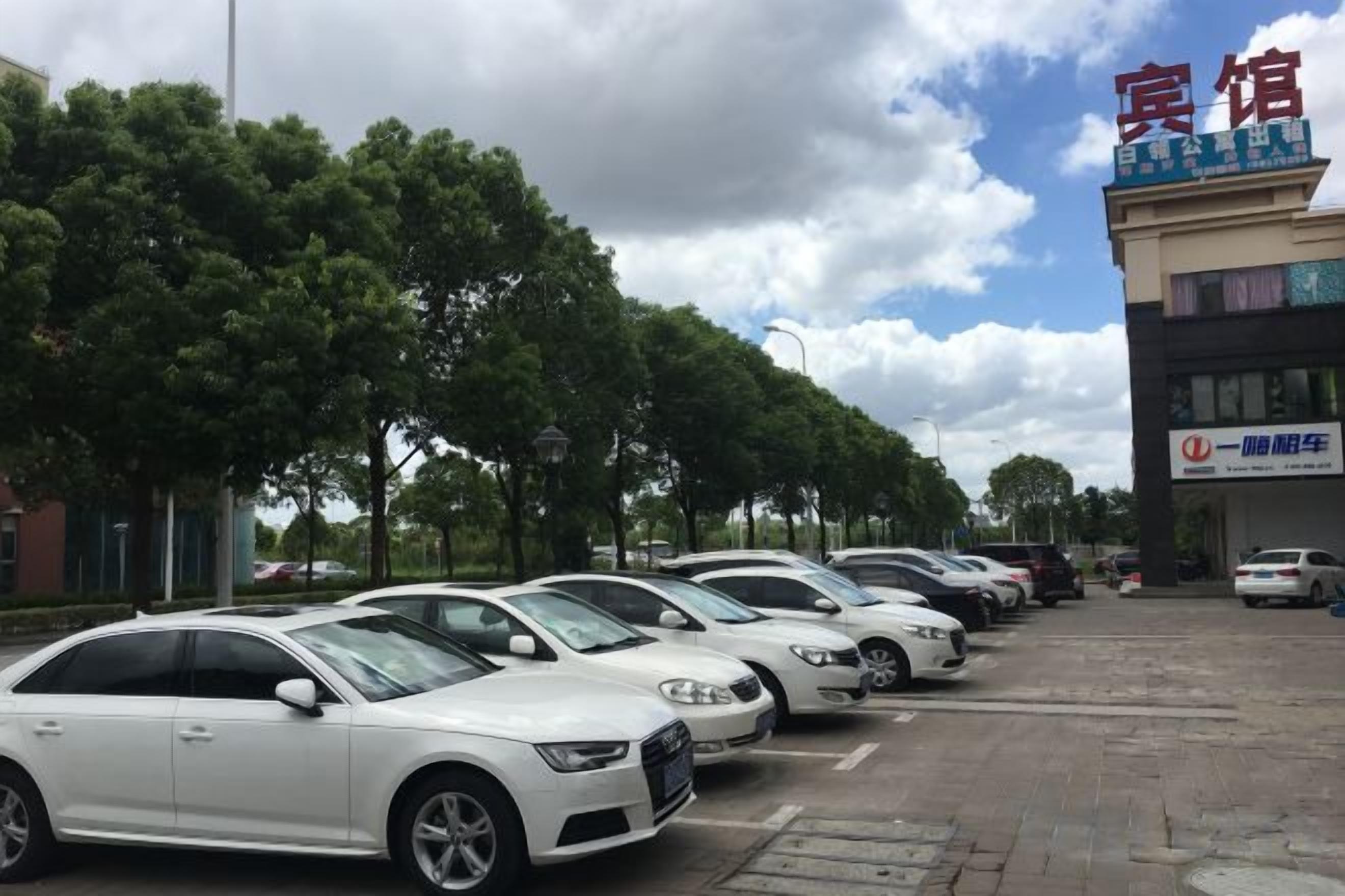 A row of parked cars in front of a building with a sign that reads '宾馆' (hotel).