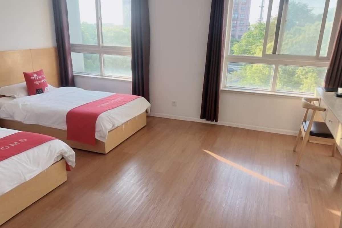 Une chambre d’hôtel avec deux lits, un bureau et de grandes fenêtres.