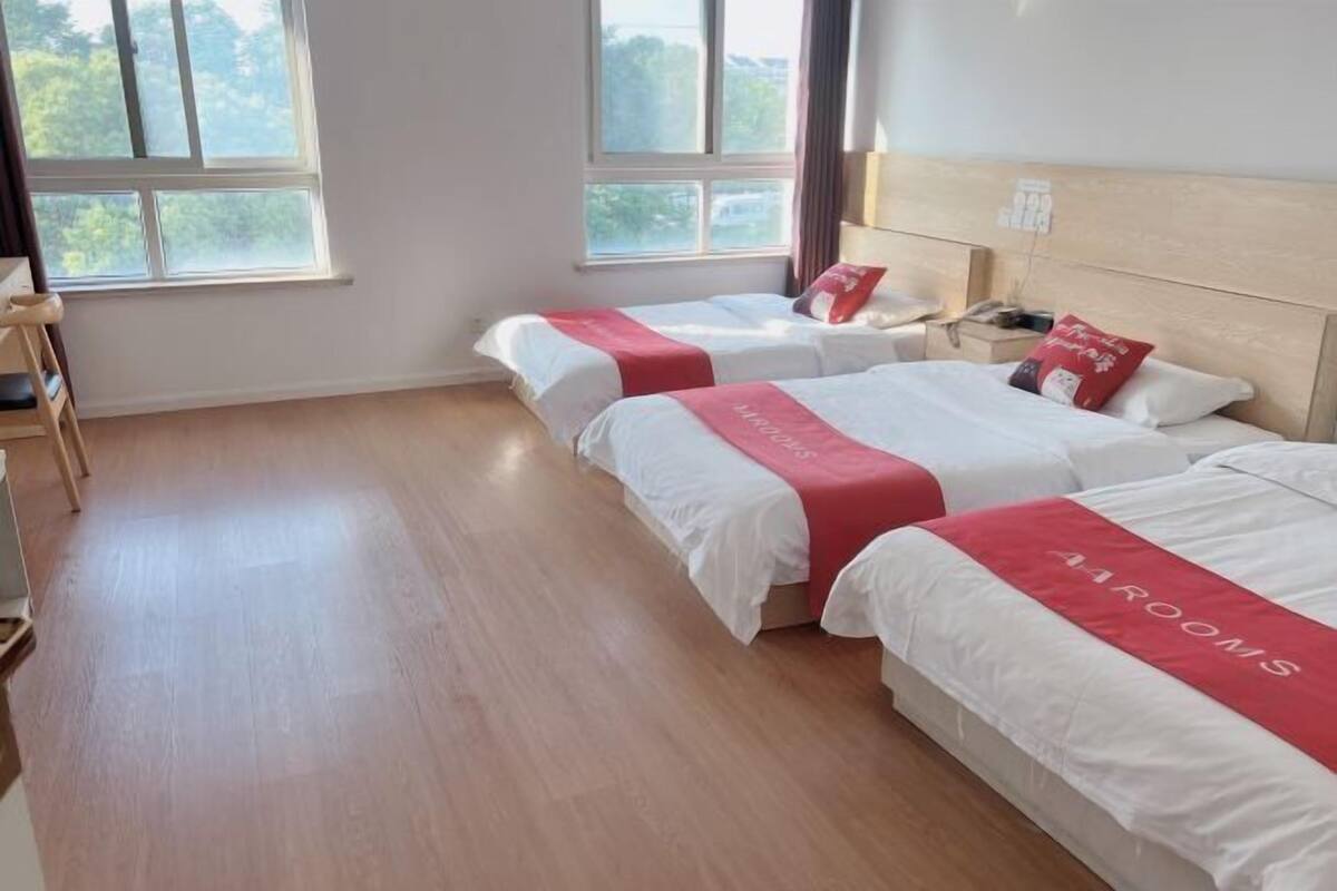 Une chambre d’hôtel avec deux lits, un plancher en bois et de grandes fenêtres.