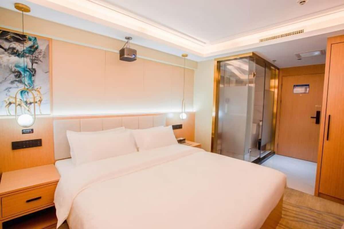 A hotel room with a bed, bedside table, nightstand, wall art, and a sliding door closet.