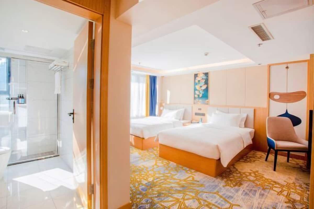 A hotel room with two beds, a shower, and a view of the outdoors.