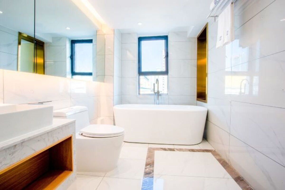 A modern bathroom with a white bathtub, a toilet, and a vanity with a mirror.