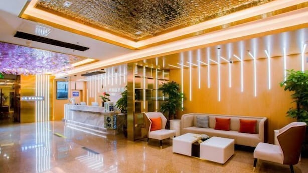 Un vestíbulo moderno con mostrador de recepción, zona de estar e iluminación decorativa.