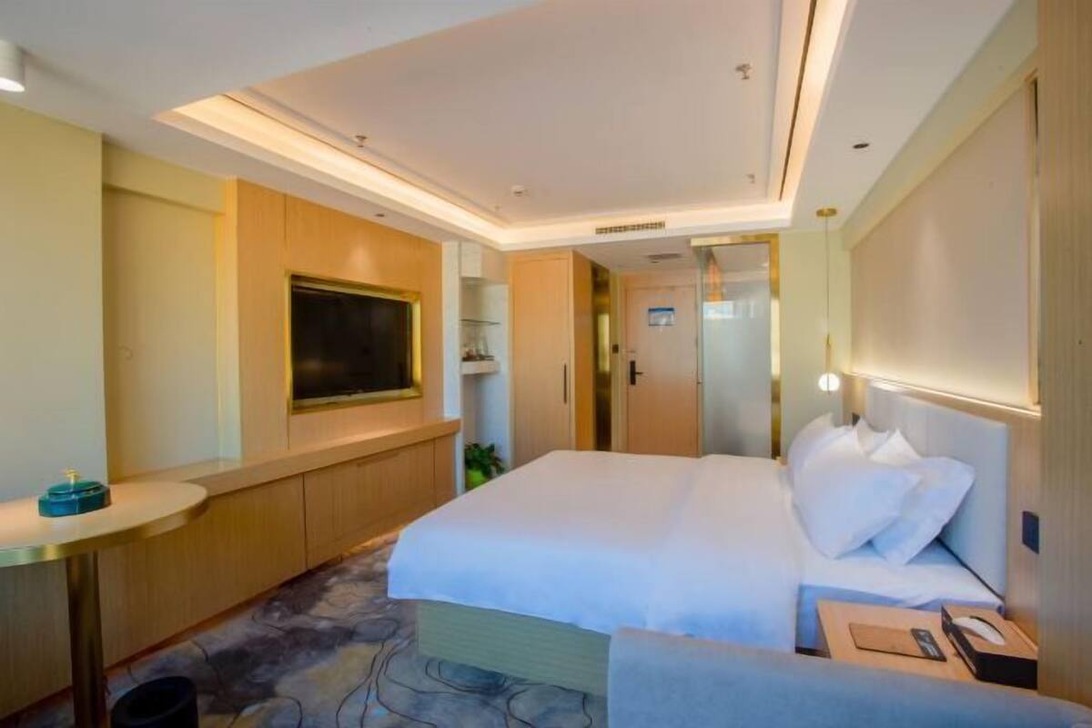 A hotel room with a bed, a TV, a desk, and a mirror.