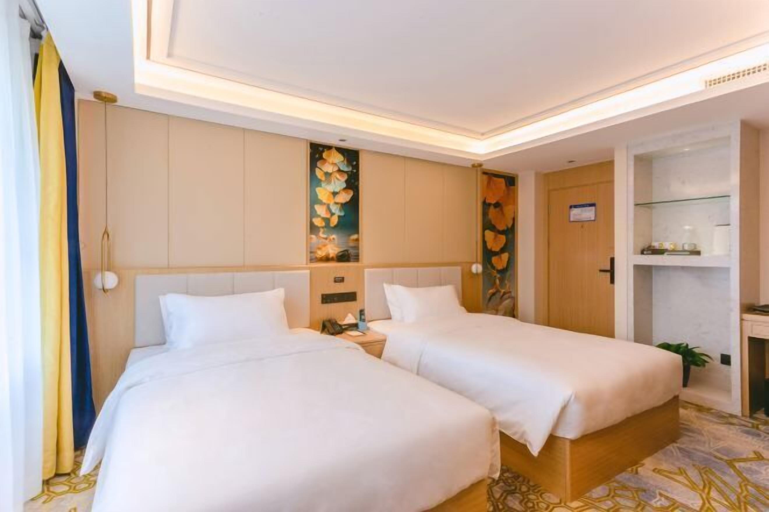 Habitación de hotel con dos camas, un escritorio, una silla, una mesita y un cuadro decorativo en la pared.